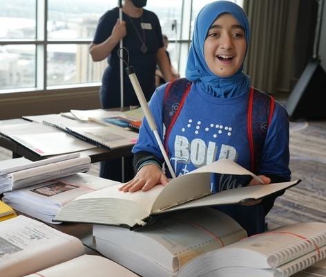  A blind child smiles brightly while reading a Braille book