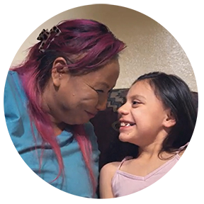 Mother and daughter lean towards each other smiling.
